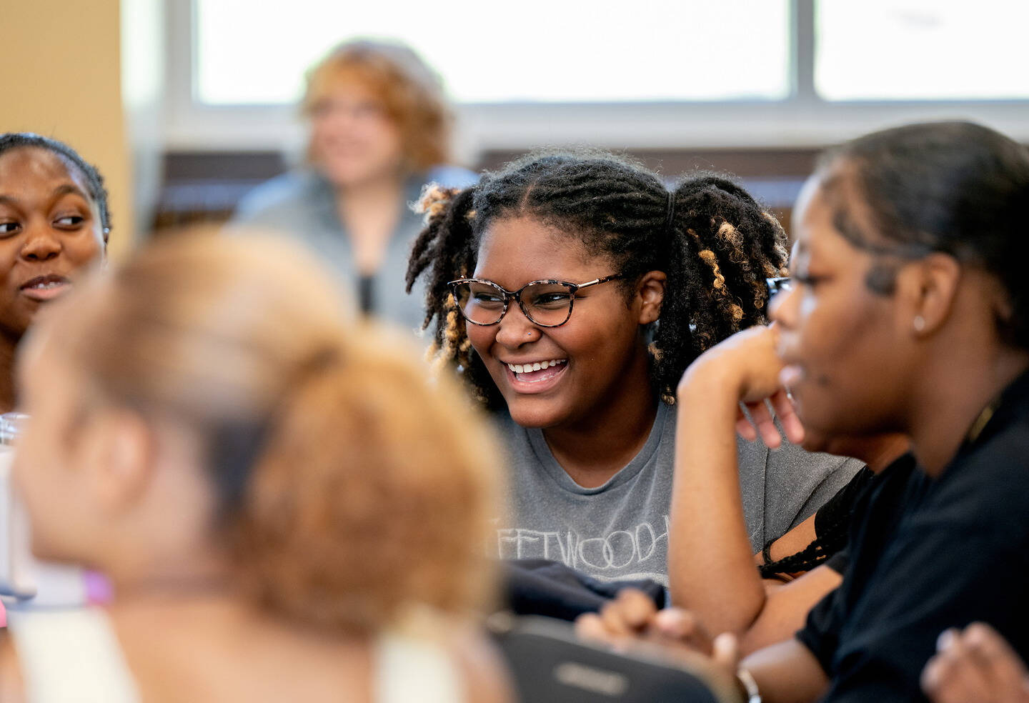 A group of young people are gathered together, with one smiling warmly while others engage in conversation.